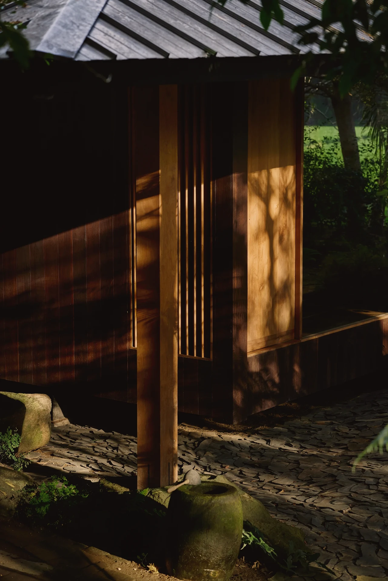 Late light falling across the timber screen and stone court